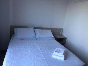 ジョアンペソアにあるMAR DO CABO BRANCO YELLOW residenceのベッド1台(青いシーツ、タオル2枚付)