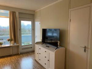 a living room with a flat screen tv on a dresser at PANORAMIC FeWo SEESCHWALBE - Pool - Familien - strandnah - Hunde in Sierksdorf