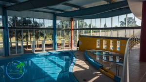 a swimming pool in a building with windows at Palmares Apart Termal in Termas de Guaviyú