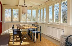 - une salle à manger avec une table, des chaises et des fenêtres dans l'établissement Amazing Home In Tvker With Kitchen, à Tvååker