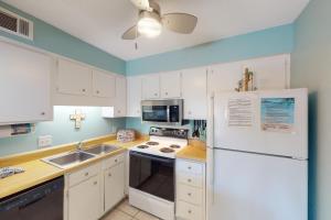 a kitchen with white cabinets and a white refrigerator at Sea Cabin 2D in Destin