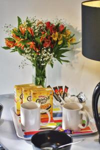 een tafel met twee kopjes en een vaas met bloemen bij Beaconsfield Hotel in Londen