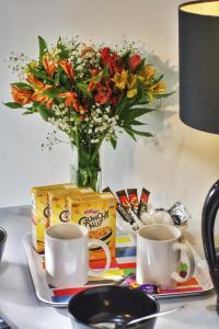 a table topped with a cup of coffee and a vase of flowers at Beaconsfield Hotel in London