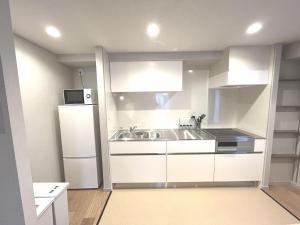 eine weiße Küche mit einer Spüle und einem Kühlschrank in der Unterkunft KLASSO Tokyo Sumiyoshi Apartments in Tokio