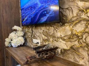 a television on a stone wall with flowers on a table at Tara Luxury Homes in Solan