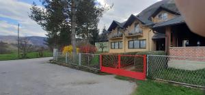 uma casa com um portão vermelho em frente em Smještaj na selu Porodica Gvozdenac em Šipovo