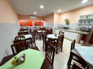 a restaurant with tables and chairs and a kitchen at Hotel Savana in Olímpia