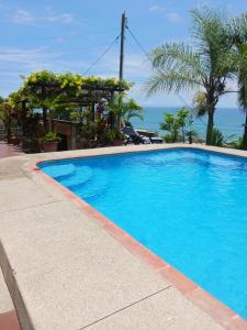 une piscine bleue avec l'océan en arrière-plan dans l'établissement Relax en Aguaclara, su Castillo de Arena soñado!, à Ballenita