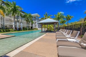 a row of chaise lounge chairs next to a swimming pool at Absolute Luxury Marina Lifestyle at The Port of Airlie Beach in Airlie Beach