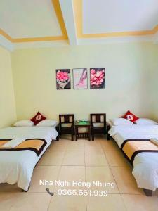 een kamer met 2 bedden en 2 tafels bij Nhà Nghỉ Hồng Nhung in Mai Chau