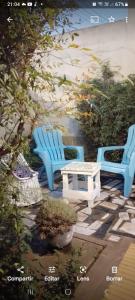 2 chaises bleues et une table dans un jardin dans l'établissement chalet de tata, à Tandil