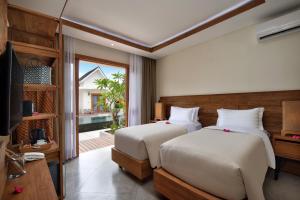 a bedroom with two beds and a tv and a window at Ponte Villas in Gili Trawangan