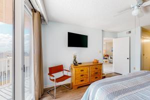 Un dormitorio con una cama, un televisor y una silla. en Buena Vista 405, en Gulf Shores