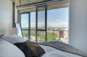 1 dormitorio con cama y ventana grande en Les Immeubles Charlevoix - Le 760212, en Quebec