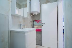 een witte badkamer met een wastafel en een spiegel bij Laurel Apartments in Tisno