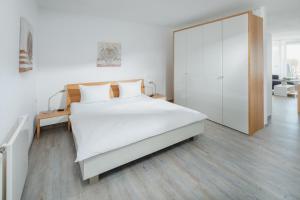 Dormitorio blanco con cama grande y armario en Meerliebe en Norderney