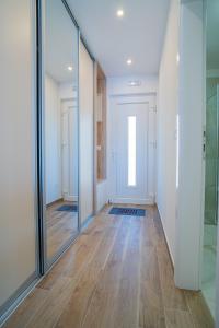 a hallway with glass doors and a wooden floor at Laurel Apartments in Tisno