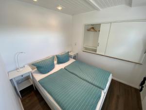 um pequeno quarto com uma cama e um espelho em Hafenloft App 4 em Norderney