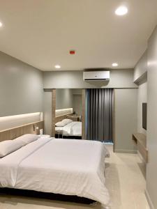- une chambre avec un grand lit blanc et une télévision dans l'établissement Synsiri Lat Phrao 83, à Ban Zong Katiam