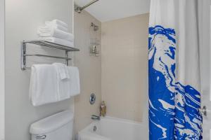 a bathroom with a white toilet and a blue shower curtain at Daytona Beach Resort Ocean Front Condo in Daytona Beach
