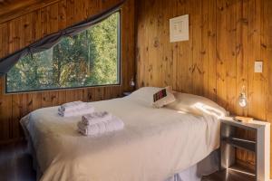 1 dormitorio con 1 cama grande y toallas. en Complejo Playa Bonita en San Martín de los Andes