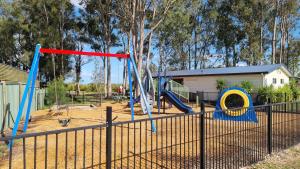 un parque infantil con columpios azules y rojos en BIG4 Karuah Jetty Holiday Park, en Karuah