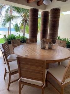 a wooden table and chairs in a patio with palm trees at Stunning beachfront house w/ private pool. in Zihuatanejo
