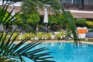 una piscina con sombrilla y algunas plantas en Amihan Resort, en Panglao