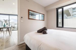 ein weißes Schlafzimmer mit einem großen Bett und einem Tisch in der Unterkunft Amazing Luxury Apartment & so close to the CBD - 01756 in Melbourne