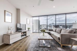 ein Wohnzimmer mit einem Sofa und einem TV in der Unterkunft Amazing Luxury Apartment & so close to the CBD - 01756 in Melbourne