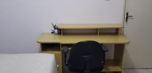 a desk with a black chair sitting in front of it at Quarto em Apartamento Centro in Criciúma
