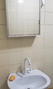 a bathroom with a sink and a mirror at Quarto em Apartamento Centro in Criciúma