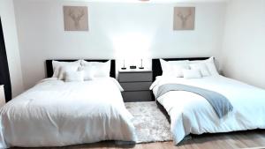 2 łóżka w sypialni z białymi ścianami i drewnianą podłogą w obiekcie Highrise luxury two bedroom condo in Downtown Atlanta within minutes!! w Atlancie