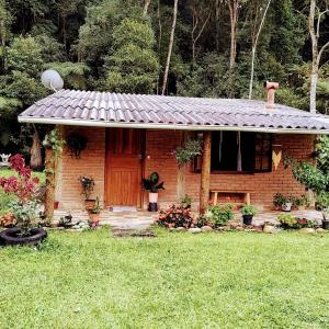 a brick house with a wooden door in a yard at Chalé Vale das Flores - Visconde de Mauá Rj in Visconde De Maua
