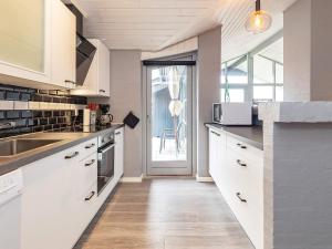 cocina con armarios blancos, fregadero y ventana en Holiday home Vestervig XLI, en Vestervig