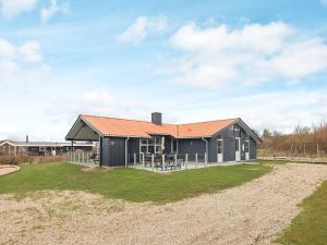 una casa negra con techo rojo en un campo en Holiday home Vestervig XLI en Vestervig