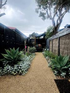 a garden with a fence and a bunch of plants at Cape Colonnades alleyway in Cape Woolamai