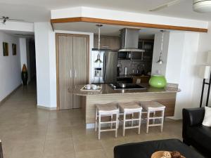 a kitchen and living room with a counter and stools at Marbella Towers - Ocean Front in Juan Pedro
