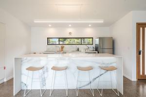 una cucina bianca con bancone bianco e sgabelli di Toad Hall - Cottage a Tintenbar