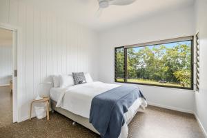 una camera da letto con un letto e una grande finestra di Toad Hall - Cottage a Tintenbar