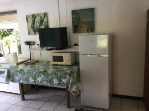 a kitchen with a table with a refrigerator and a microwave at VAIHEI 22 in Puahua