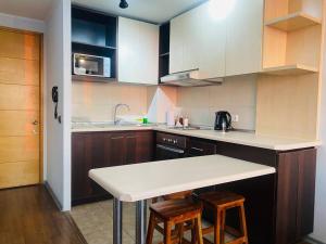 a kitchen with a white counter top and wooden cabinets at Céntrico Apartamento Frente al Metro in Santiago