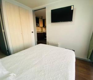 a bedroom with a white bed and a flat screen tv at Céntrico Apartamento Frente al Metro in Santiago