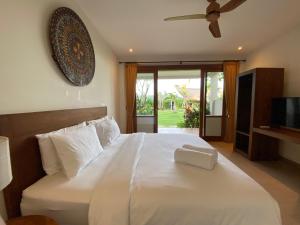 a bedroom with a large white bed with a ceiling fan at Bombora Balangan Resort in Ungasan