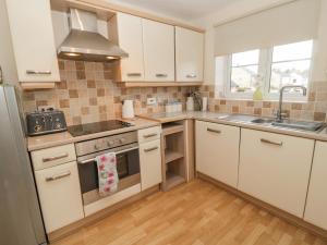 a kitchen with white cabinets and a sink and a stove at Ramblers Cottage in Glanton