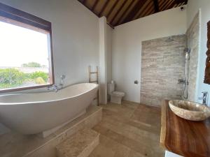 een badkamer met een groot bad en een raam bij Bombora Balangan Resort in Ungasan