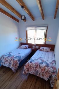 two beds in a bedroom with a window at Cabaña Playa Rosada in Valdivia