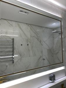 La salle de bains est pourvue d'une fenêtre en verre et d'un mur en marbre. dans l'établissement LOFT CENTRO GRAMADO, à Gramado