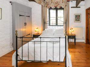 una camera da letto con un letto con lenzuola bianche e una finestra di The Dairy a Corwen