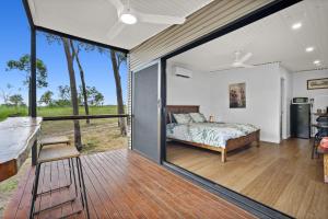 een slaapkamer met een bed en een groot glazen raam bij Litchfield Tropical Stay in Batchelor